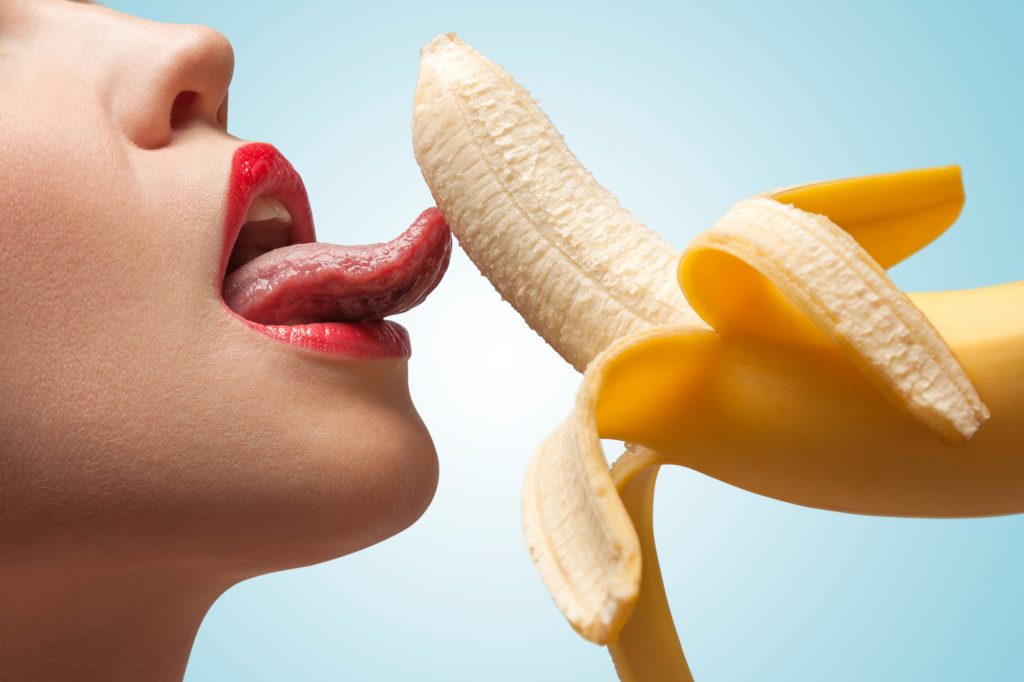 女性がバナナを舐めている写真